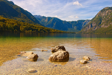 Wide angle landscape view of famous Bohinj Lake (Bohinjsko jezero), scenic mountain range against colorful vibrant sky at sunny day. Triglav National Park, Slovenia. Concept of landscape and nature