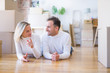 © Krakenimages.com - Young beautiful couple lying down on the floor at new home around cardboard boxes