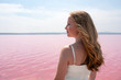 © DavidPrado - Side view of cute teenager woman wearing summer clothes standing on an amazing pink lake