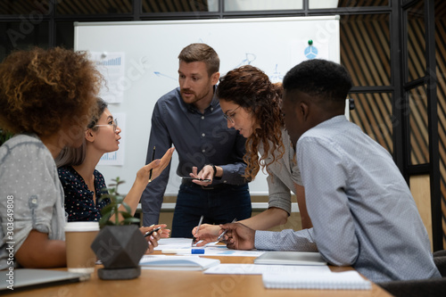 Fotomural Busy millennial group of motivated mixed race teammates discussing project