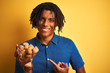 © Krakenimages.com - Afro american man with dreadlocks eating walnuts over isolated yellow background very happy pointing with hand and finger