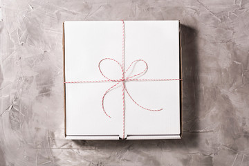 Wall Mural - Closed box of pizza tied of christmas red white string or twine in a bow on the on grey concrete background. Concept