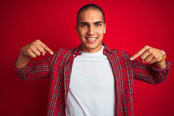 Poster - Young handsome man wearing a shirt using watch over red isolated background looking confident with smile on face, pointing oneself with fingers proud and happy.