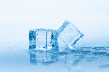 Ice two cubes square with drops water clean on blue background