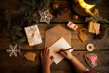 Wall Mural - Christmas wreath with pine cones,acorns and autumn berries, gifts/a child writes a letter to Santa Claus