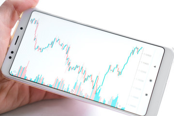 Stock market or forex trading graph and candlestick chart on mobile device in businessman hand. Economy trends idea. Online finance trading, financial investment concept. On white