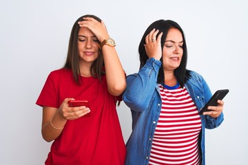 Sticker - Young beautiful women using smartphone standing over isolated white background stressed with hand on head, shocked with shame and surprise face, angry and frustrated. Fear and upset for mistake.