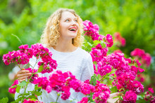 Beautiful Woman With Spring Blooming Rose Flowers. Young Smiling Girl Enjoys Pink Rose Flowers. Summer Time. Happy Woman Walking At Rose Garden. Pink Rosebush Blooming.
