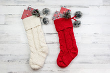 Red And White Knitted Christmas Stockings On White Wood Background