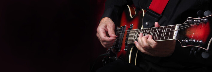 Wall Mural - Guitarist hands and guitar on a black background close up. playing electric guitar. copy spaces. 