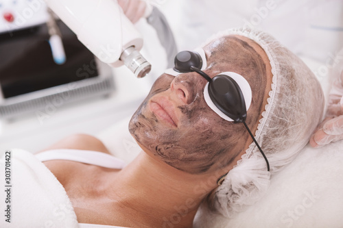 Fotografía Close up of a mature woman wearing protective eyeglasses, getting carbon laser p