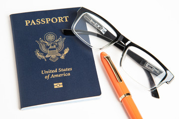 An American passport with a pair of reading glasses and an orange fountain pen.