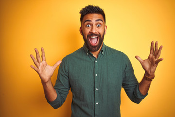 Wall Mural - Young indian businessman wearing elegant shirt standing over isolated white background celebrating crazy and amazed for success with arms raised and open eyes screaming excited. Winner concept