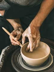 Ceramist at a pottery workshop Man is sculpting a bowl behind a rotating potter's wheel