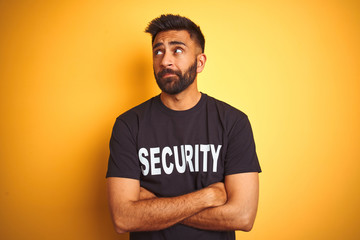 Wall Mural - Arab indian hispanic safeguard man wearing security uniform over isolated yellow background smiling looking to the side and staring away thinking.