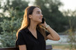© Mountains Hunter - A young girl sits on a bench in a park and makes notes. Dressed in a free style. Business woman talking on the phone with customers. Time to relax and have some coffee