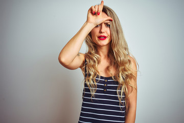 Sticker - Young beautiful woman wearing stripes t-shirt standing over white isolated background making fun of people with fingers on forehead doing loser gesture mocking and insulting.