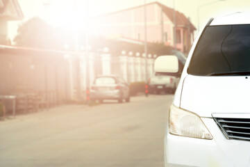 Wall Mural - Front of white car on the road in the city of residence with sunset.