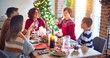 © Krakenimages.com - Beautiful family smiling happy and confident on celebration. One of them standing holding cup of water speaking speech celebrating christmas at home