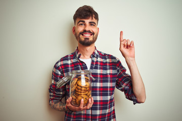 Sticker - Young man wearing bathrobe drinking cup of coffee standing over isolated white background surprised with an idea or question pointing finger with happy face, number one