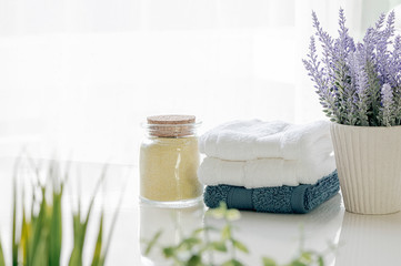 Mockup bath towels on white table with houseplant in white room, copy space for product display.