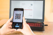 © phoderstock - Close up of hand smartphone to make mobile wallet payment via QR code scanning digital invoice from laptop screen. The QR code leads to 'Thank you so much' when scanned.
