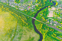 Aerial View Landscape Of Winding Small River Among The Small Town, Stream In Green Field Meadow, Top View.