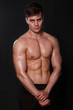 © Михаил Гута - Muscular bodybuilder posing with a naked torso against a black background. Sexy man.