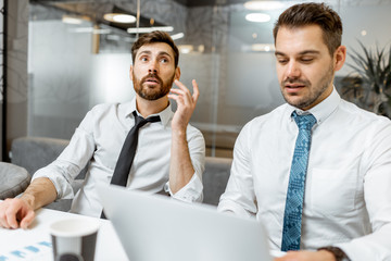 Two male employees in white shirts and tie having some business discussion in the meeting room