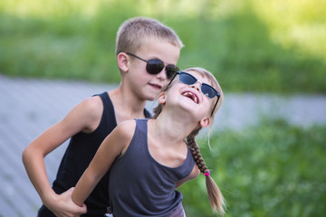 Wall Mural - Two children in black sunglasses having fun time outdoors in summer.