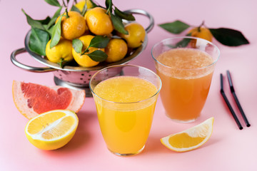 Composition with Two Glasses of Assorted Citrus Juices Detox Diet Healthy Drink Mandarine Lemon and Grapefruit Juices Raw Mandarines Pink Background Horizontal