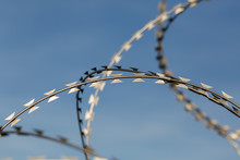OBERPFAFFENHOFEN, BAVARIA / GERMANY - Sept 28, 2019: Detail Of / Isolated View On Sharp, Metallic Razor Wire / Barbed Wire. Blue Sky In The Background. Symbol For Border, Limiting Migration, Prison.
