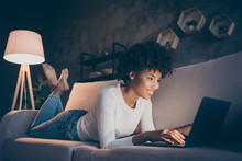 Profile Photo Of Amazing Dark Skin Curly Lady Browsing Notebook Texting Friends Lying Comfy Sofa Wear Casual Sweater Jeans Clothes Evening Lamp Light Living Room Indoors