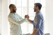 © fizkes - Mixed race male friends in eyewear shaking hands.