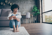 Photo Of Pretty Dark Skin Curly Lady Sitting Floor Near Sofa Sad Missing Boyfriend Looking Window Offended Wear Casual Sweater Jeans Outfit Flat Indoors
