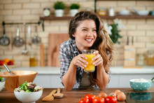 Young Woman In Kitchen. Beautiful Woman In Modern Kitchen Drinking Orange Juice. 