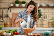 © JustLife - Young woman in kitchen. Beautiful woman preparing healthy food.