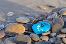 Blue Stone With The Inscription Be Happy On The Beach Among The Stones
