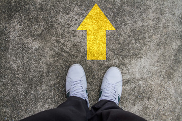 standing on a tarmac road with yellow arrow print