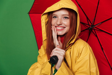 Poster - Redhead woman in yellow raincoat holding umbrella.