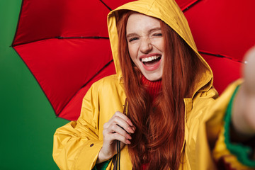 Poster - Redhead woman holding umbrella take a selfie by camera.