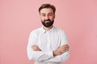 young bearded brunette man male guy with short haircut trendy hairstyle dressed in wearing white shirt formal clothes standing posing isolated over pink background