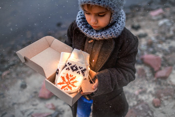 Girl in knitted grey hat opening a gift box with warm gloves