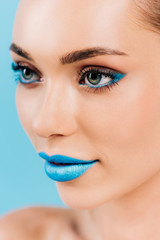 Wall Mural - close up view of beautiful woman with blue makeup isolated on blue