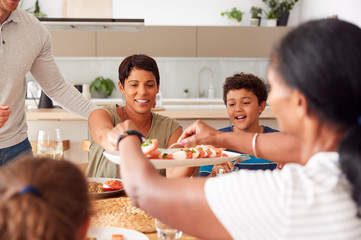 Wall Mural - Father Serving As Multi-Generation Mixed Race Family Eat Meal Around Table At Home Together