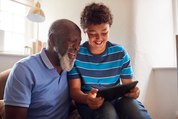 Wall Mural - Grandfather Sitting In Chair With Grandson Watching Movie On Digital Tablet Together