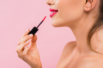 Wall Mural - cropped view of smiling naked beautiful woman with pink lips applying lip gloss isolated on pink