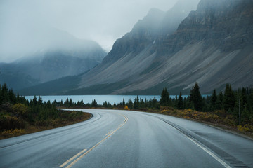 scenic road trip with rocky mountain and lake in gloomy day