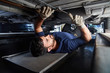 KFZ Mechaniker kontrolliert Auto Unterbodenschutz