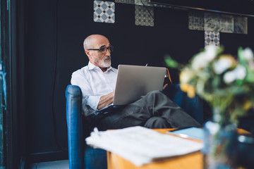 Elderly man with glasses working on laptop